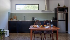 Una cocina moderna con armarios oscuros, una mesa de madera y un ventanal sobre el lavamanos.