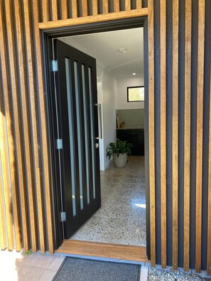 Una entrada moderna con puerta de madera y suelo de hormigón.