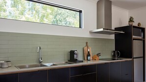 Una cocina moderna con un ventanal grande, un lavamanos empotrado y un refrigerador negro.