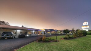 A motel with a signboard, a parking area, and a grassy lawn. - Glen Innes Motel (Glen Innes)