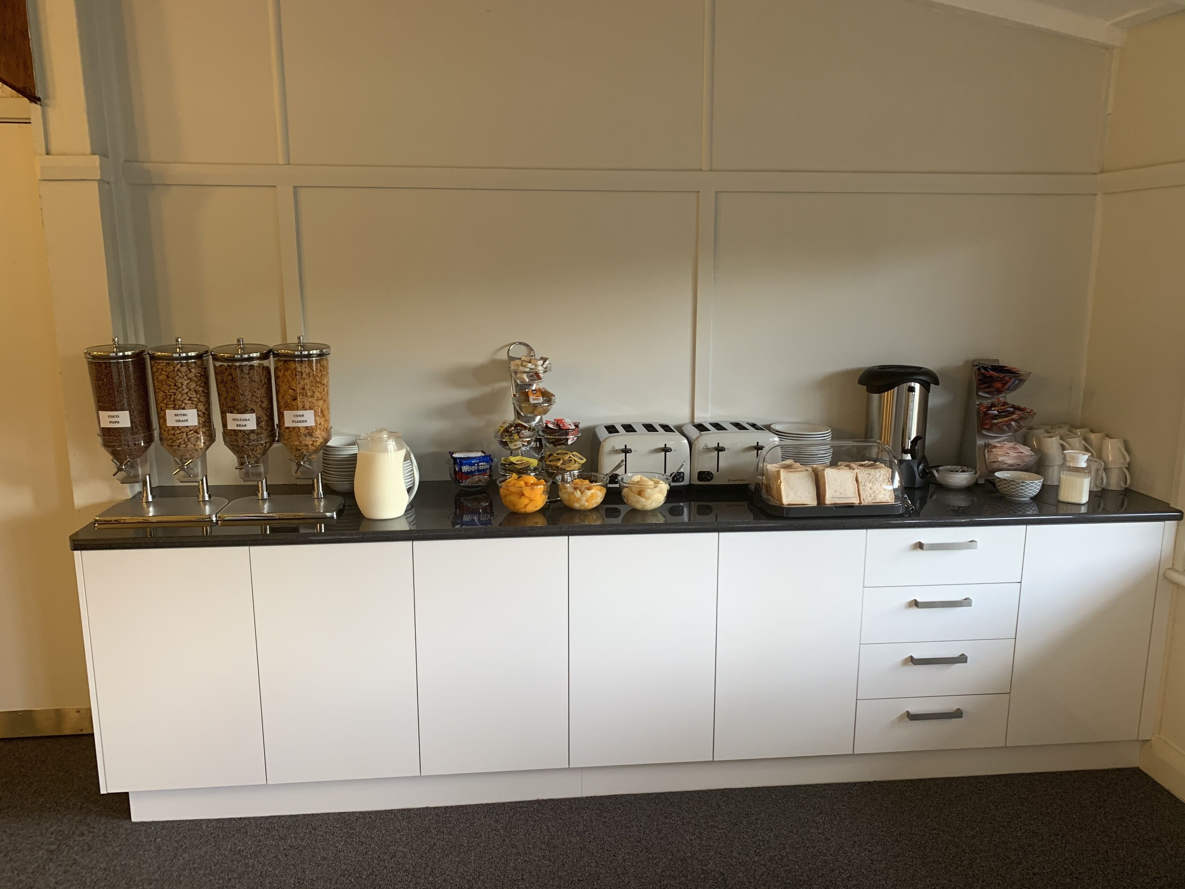 A breakfast bar with various food items and a coffee machine.