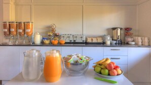 Ein Frühstücksbuffet mit verschiedenen Speisen, darunter Obst, Getreideprodukte und Getränke.