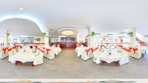 A spacious indoor dining area with round tables and chairs, each adorned with red sashes. - Asia Hotel Can Tho (Can Tho)