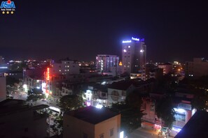 A nighttime cityscape with illuminated buildings and a prominent hotel with a blue sign.