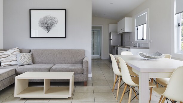 A modern living room with a grey sofa, a white coffee table, and a framed artwork on the wall. - NRMA Stockton Beach Holiday Park (Stockton)
