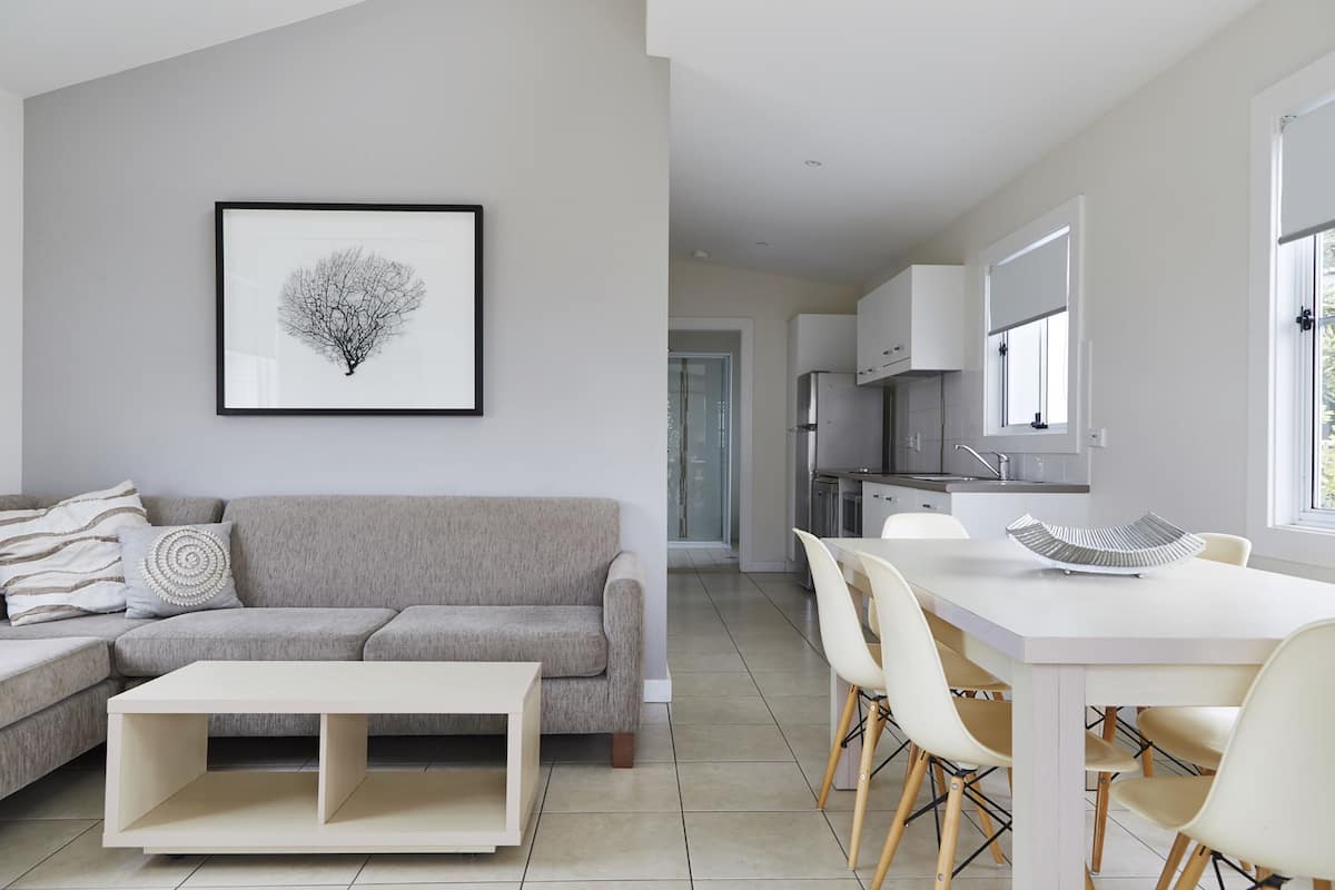 Un salon moderne avec un canapé gris, une table basse blanche et une œuvre d’art encadrée accrochée au mur.
