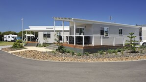 A modern two-story house with a covered patio, a driveway, and a landscaped garden area. - NRMA Stockton Beach Holiday Park (Stockton)