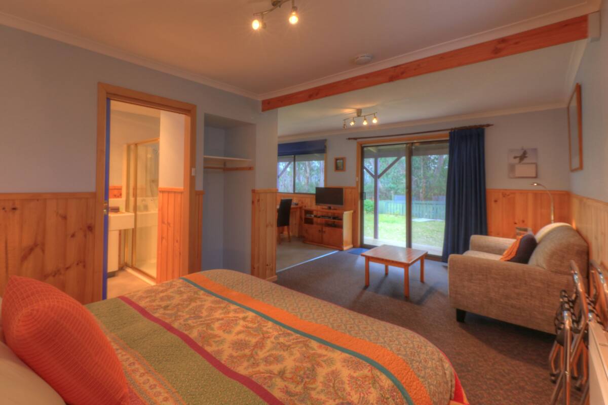 A bedroom with a bed, a desk, and a chair. There is a sliding glass door leading to a balcony.