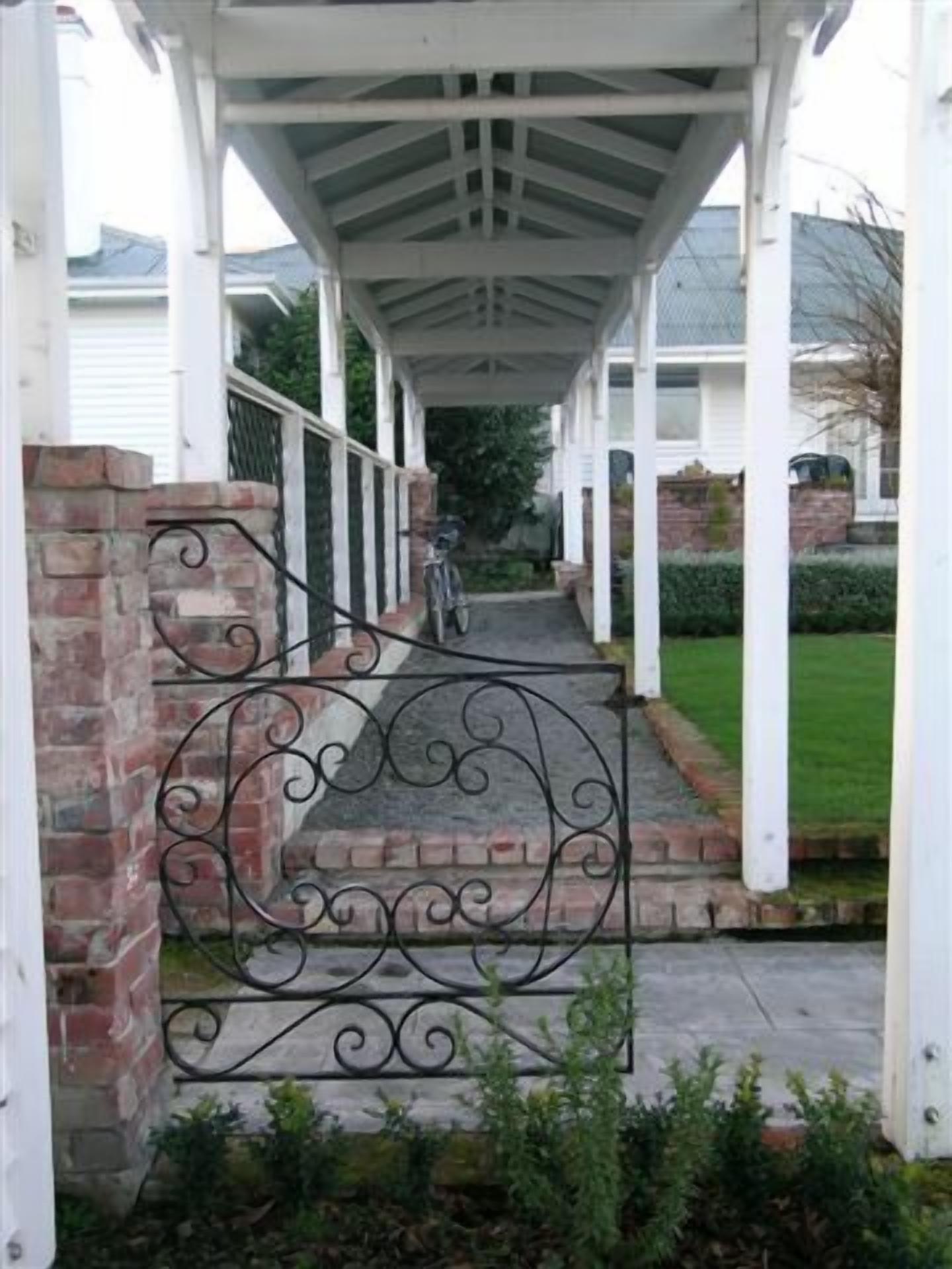 A covered porch with a brick wall and a metal gate.