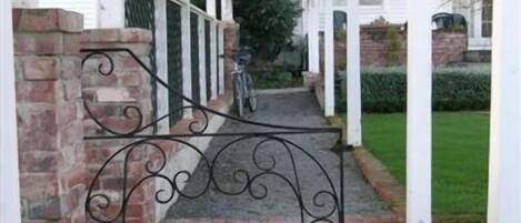 A covered porch with a brick wall and a metal gate.