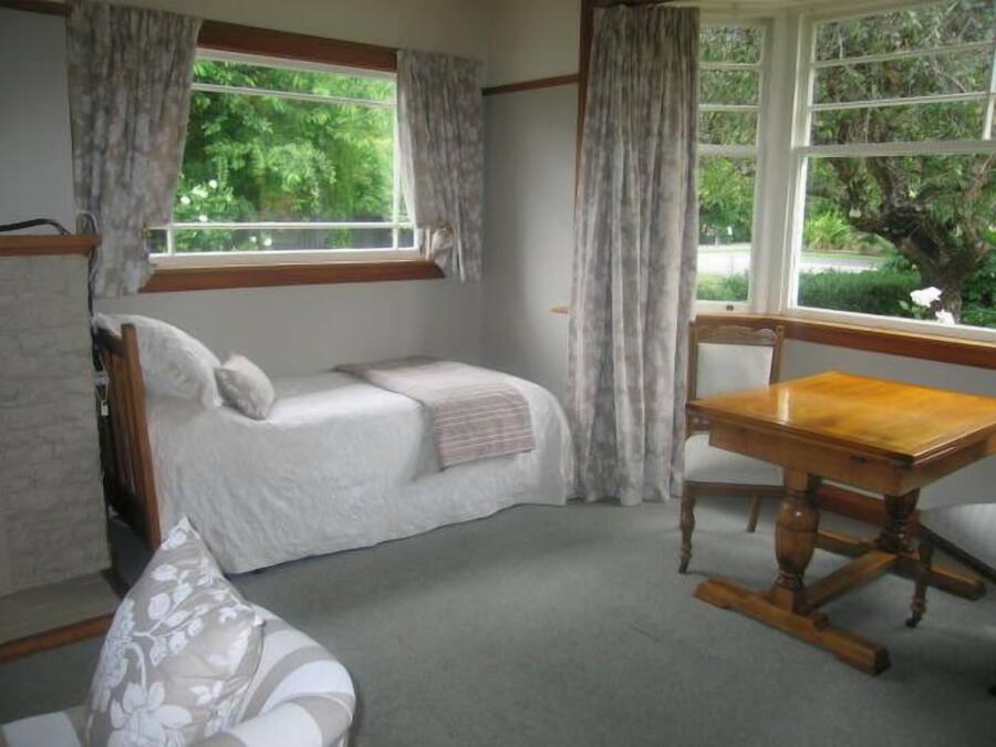 Un dormitorio con una cama, una mesa de madera y una ventana con cortinas.