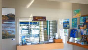 Un área de recepción con un letrero que dice 'Acapulco', una ventana con persianas y varios carteles informativos.