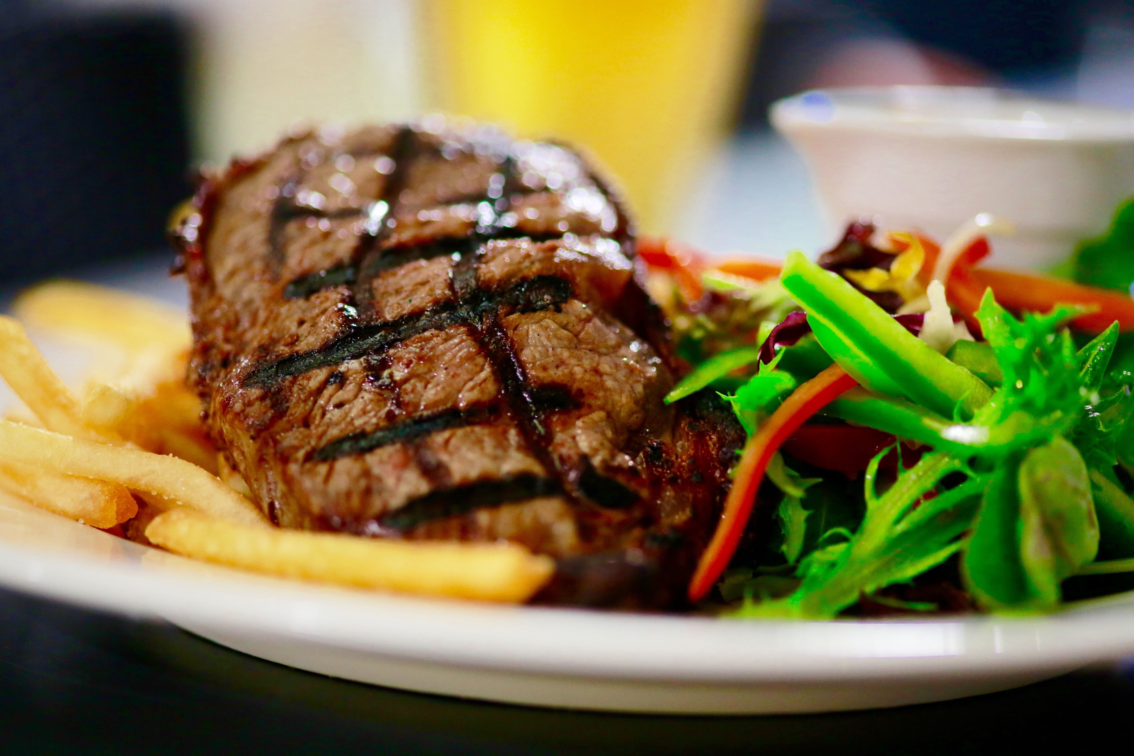 Une assiette avec un steak grillé, des frites et une salade.