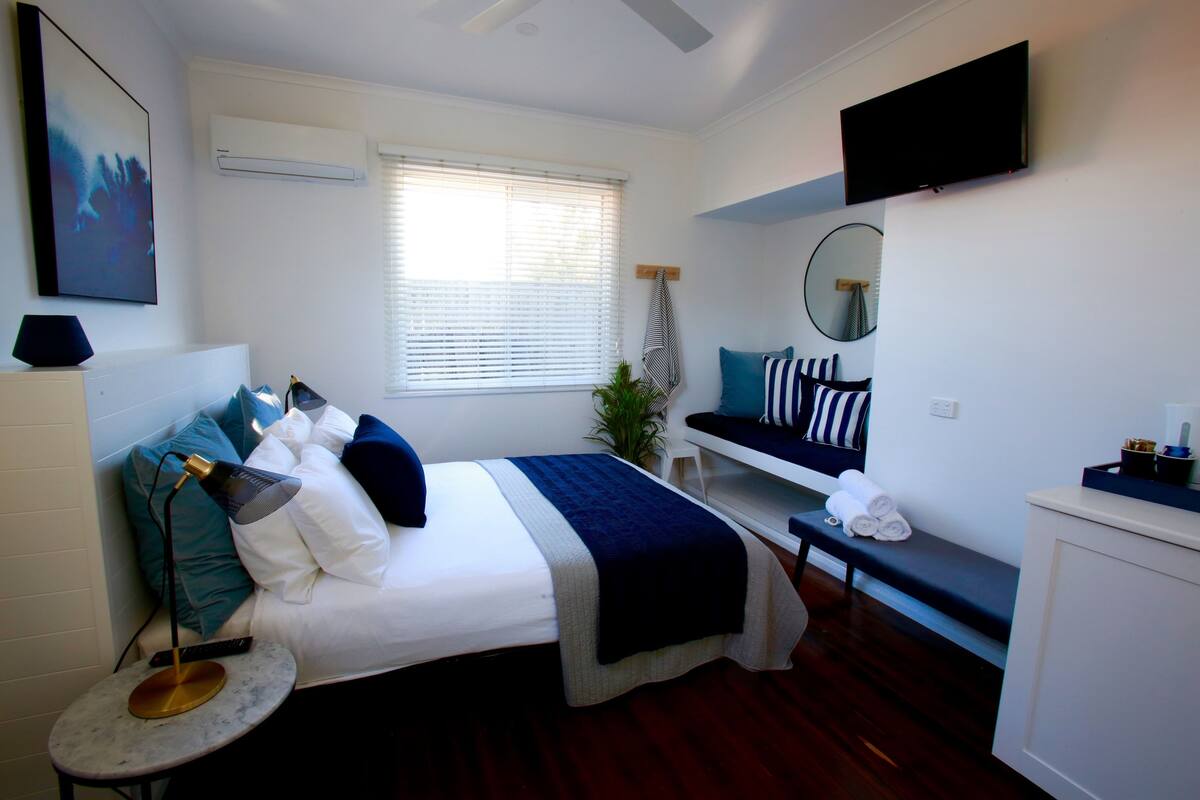 A neatly arranged bedroom with a bed, bedside table, and a bench.