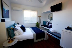 A neatly arranged bedroom with a bed, bedside table, and a bench. - Tea Gardens Hotel (Tea Gardens)