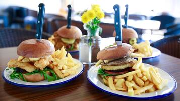 Une table avec deux assiettes de nourriture, chacune contenant un hamburger et des frites, ainsi qu’un salier et un poivrier.