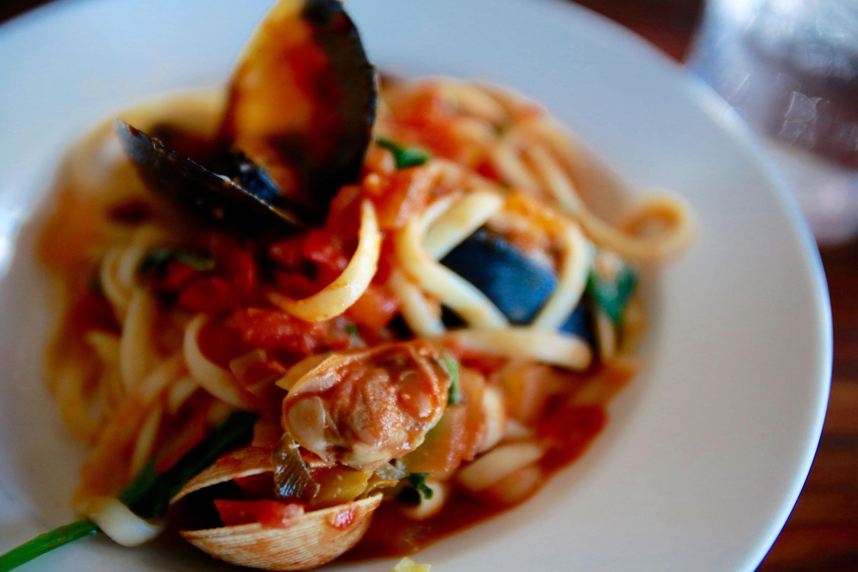 A plate of pasta with mussels and vegetables.