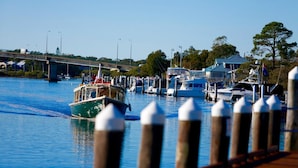 Un puerto deportivo con barcos amarrados, un puente al fondo y un muelle de madera con defensas.