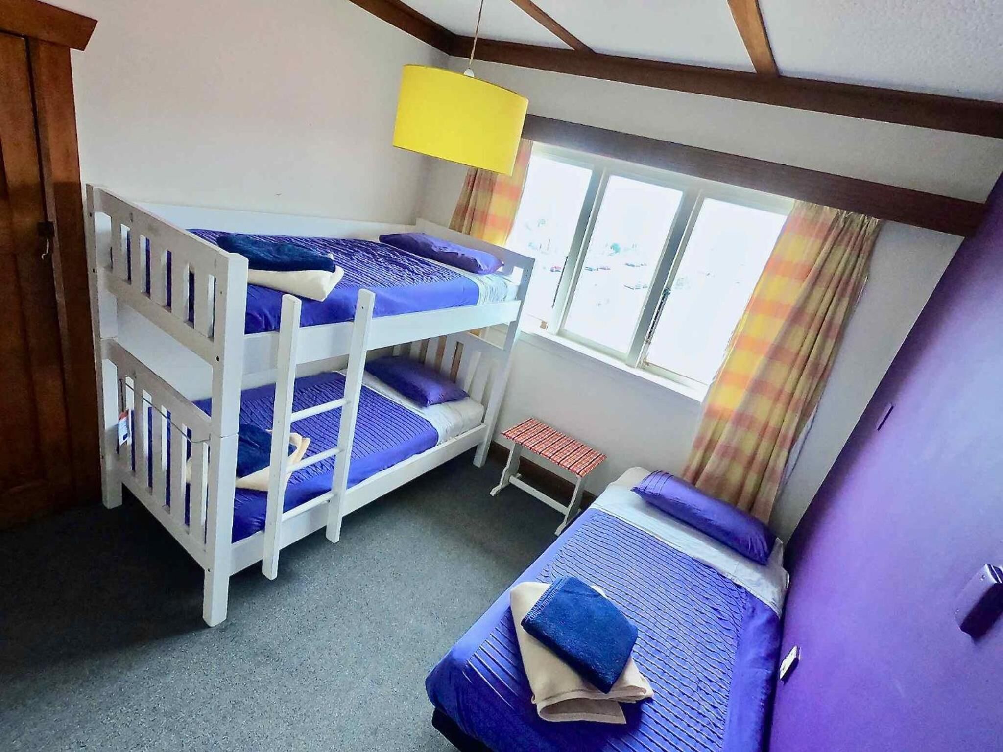 A bunk bed room with a small table and a window.