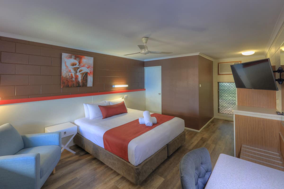 Une chambre d’hôtel équipée d’un lit, d’un bureau, d’une chaise, d’une télévision et d’un ventilateur de plafond.