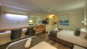 A hotel room with two beds, a desk with chairs, a television, a microwave, and a painting on the wall. - Billabong Lodge Motel (Rosslea)