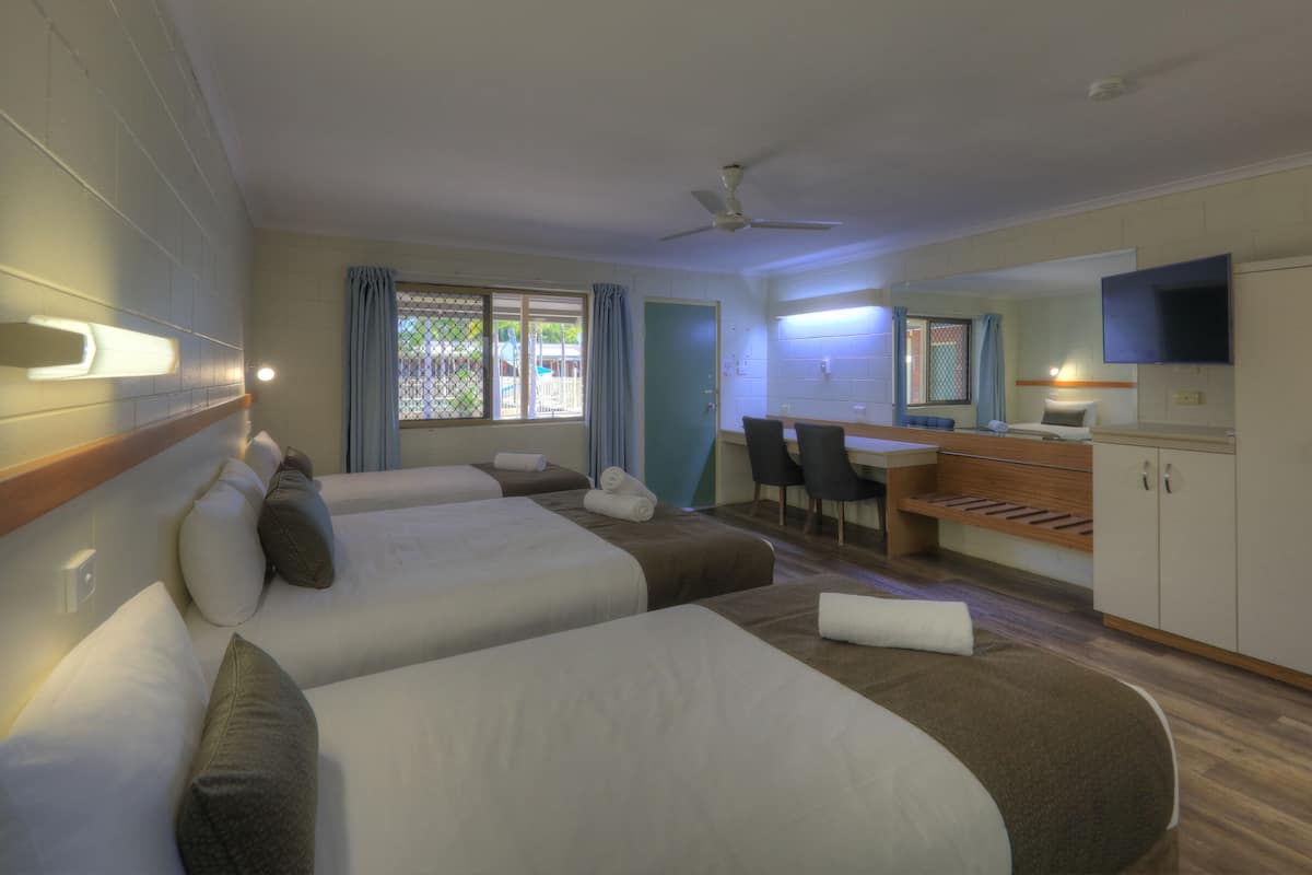 Une chambre d’hôtel avec deux lits, un bureau, une chaise, une télévision et une armoire.