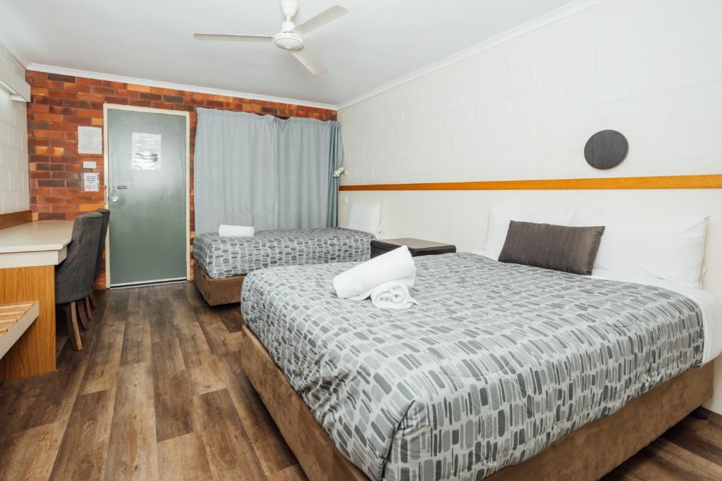 A hotel room with two beds, a desk, and a chair.
