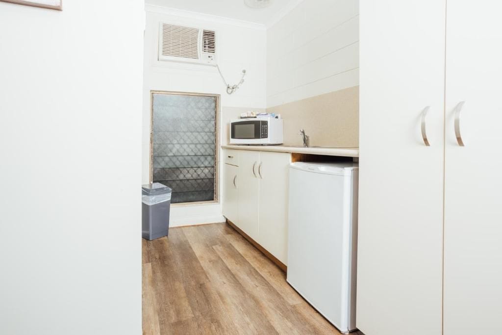 Une cuisine compacte avec des meubles blancs, un four à micro-ondes et un petit réfrigérateur.