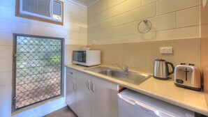 A compact kitchen with a sink, a microwave, a kettle, and a toaster. - Billabong Lodge Motel (Rosslea)