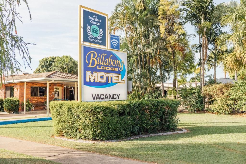 A sign for Billabong Lodge Motel with a 'Vacancy' label, surrounded by greenery and palm trees.