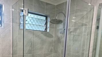 A modern bathroom with a glass-enclosed shower, a wooden vanity, and a large mirror.