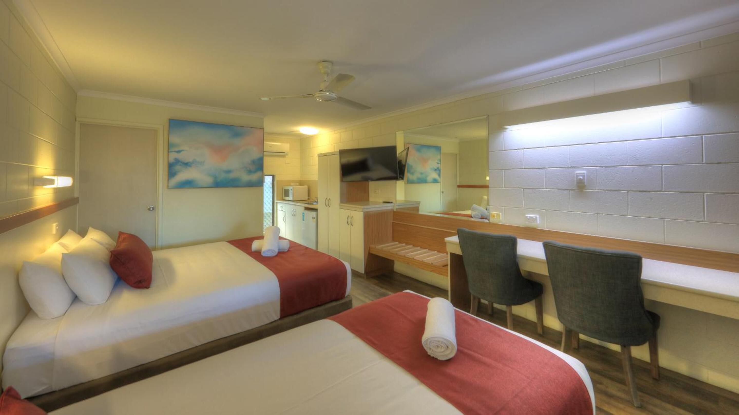 Una habitación de hotel con dos camas, un escritorio, una silla, un televisor y un baño.