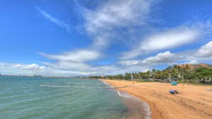 A beach with clear blue water, a sandy shore, and a few palm trees. - Billabong Lodge Motel (Rosslea)