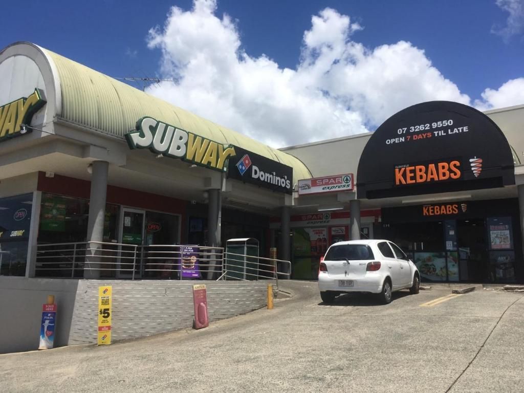 A SUBWAY and KEBABS restaurant with a white car parked in front.
