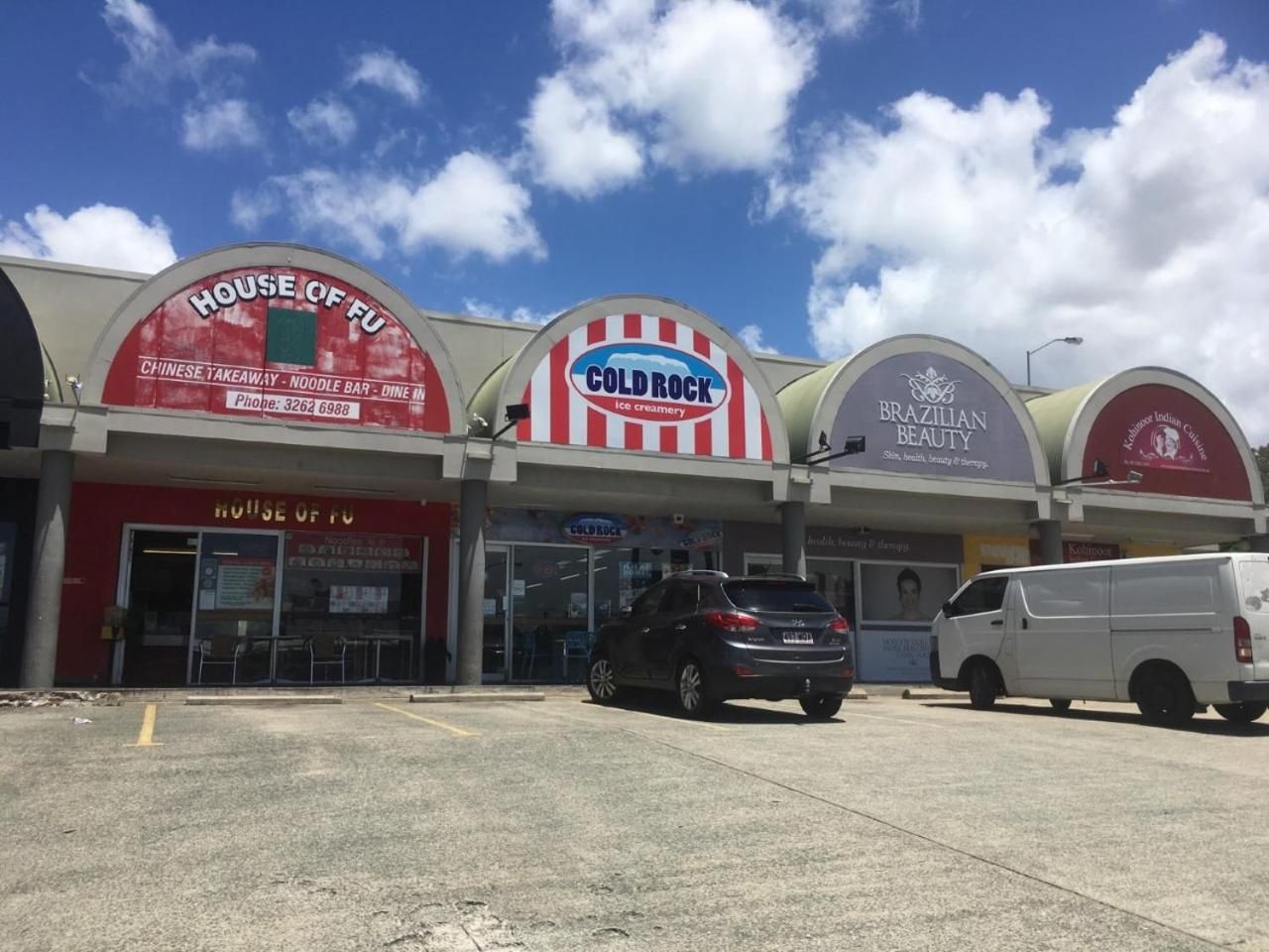 A commercial building with multiple storefronts including a Chinese takeaway, noodle bar, and Brazilian beauty salon.