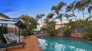 Une piscine avec des chaises longues et des palmiers.