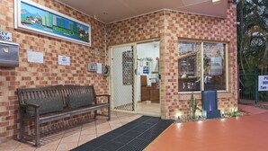 Un bâtiment en briques avec un banc à l’extérieur, une porte portant l’inscription « bureau » et un panneau indiquant « dépôt de clés ».