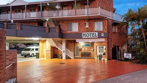 Un motel composé d’un bâtiment à deux étages, doté d’un balcon et d’un panneau indiquant les heures d’ouverture de la piscine.