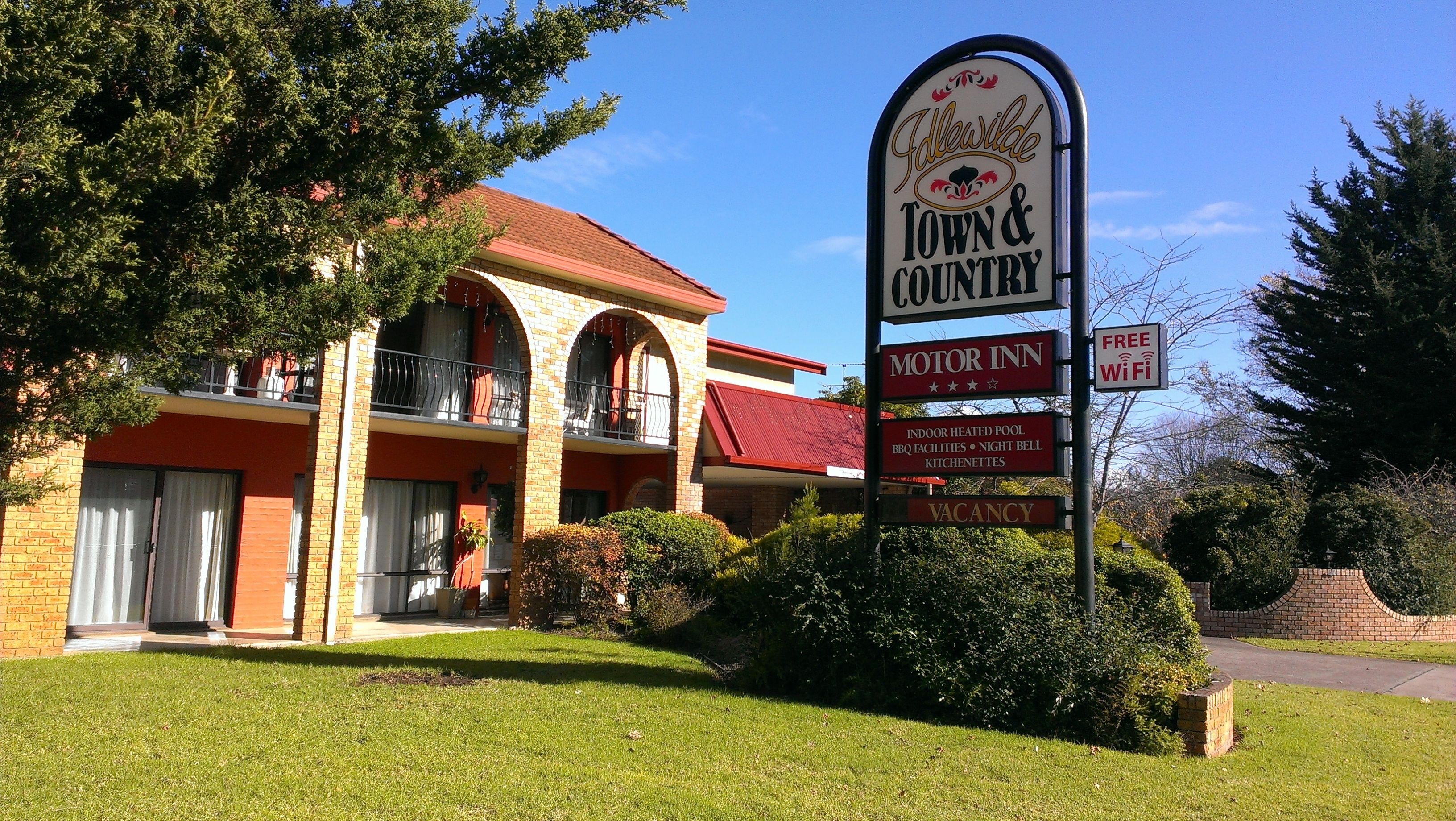 A motel with a sign indicating it offers free WiFi, indoor heated pool, BBQ facilities, night bell kitchens, and a motor inn.
