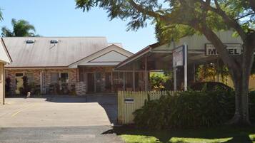 A motel with a brick facade, a covered parking area, and a sign indicating a pet-friendly policy.