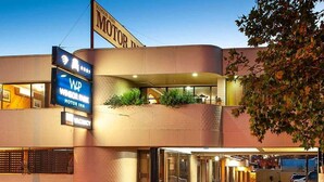 A building with a 'MOTOR INN' sign, a green convertible parked in front, and a 'WINSOR PARK' sign above. - Albury Winsor Park Motor Inn (Albury)