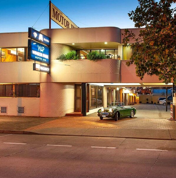 A building with a 'MOTOR INN' sign, a green convertible parked in front, and a 'WINSOR PARK' sign above.
