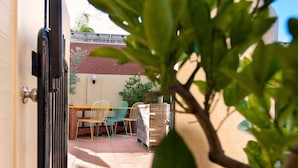 An outdoor patio with a wooden table and chairs, a brick wall, and a potted plant in the foreground. - Albury Winsor Park Motor Inn (Albury)