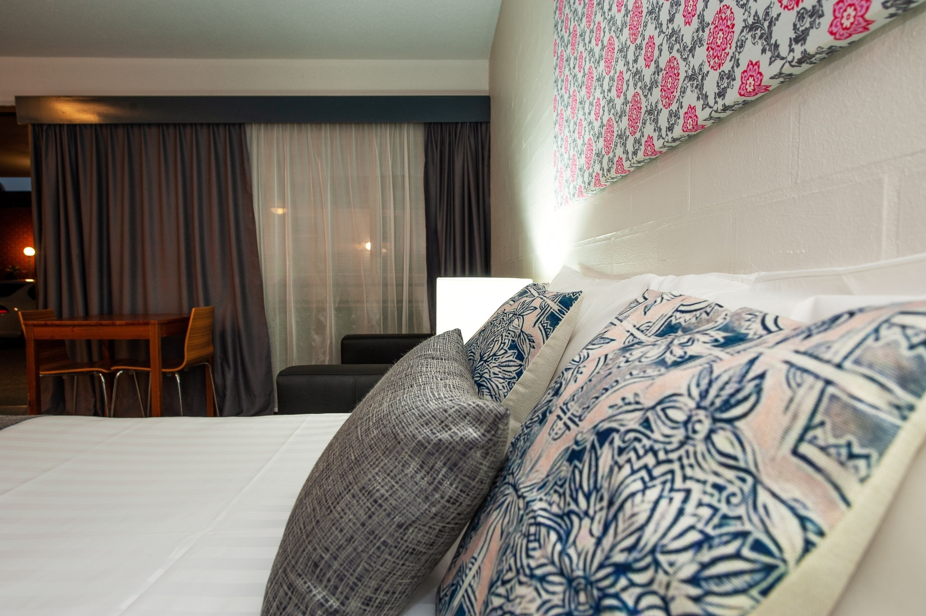 Habitación de hotel con cama, silla, escritorio y pared con diseño.