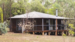 A wooden cabin with a balcony, surrounded by trees.