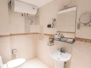 A bathroom with a toilet, sink, mirror, and towel rack.