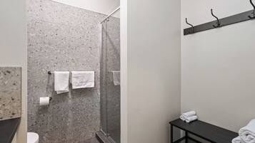 A bathroom with a shower, toilet, and a towel rack with towels.