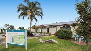 A building with a solar panel roof, a palm tree, and a signboard. - Carrum Downs Motel (Carrum Downs)