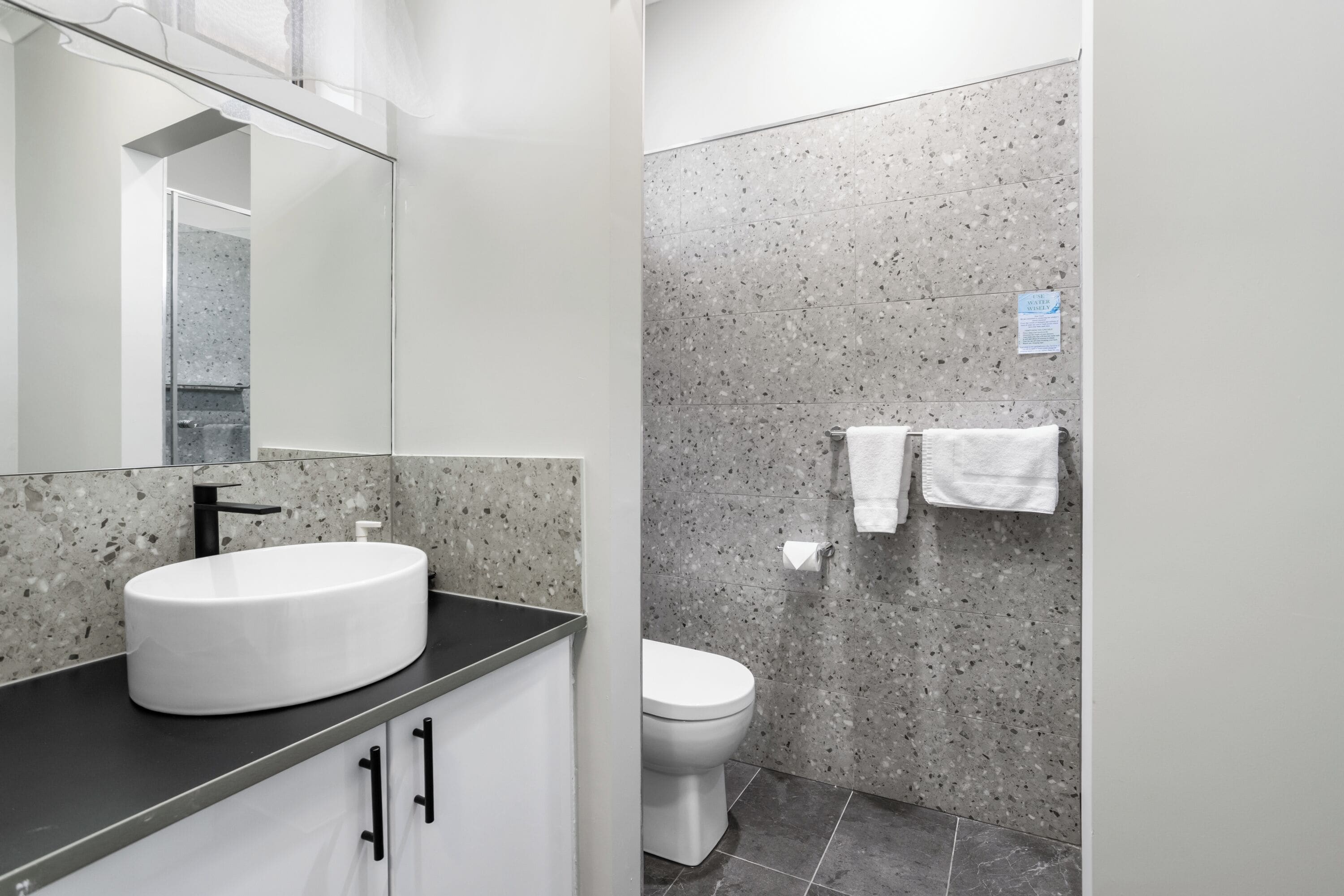 A bathroom with a white sink, a mirror, a toilet, and a towel rack.