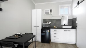 A compact kitchen with white cabinets, a black refrigerator, a microwave, and a sink. - Carrum Downs Motel (Carrum Downs)